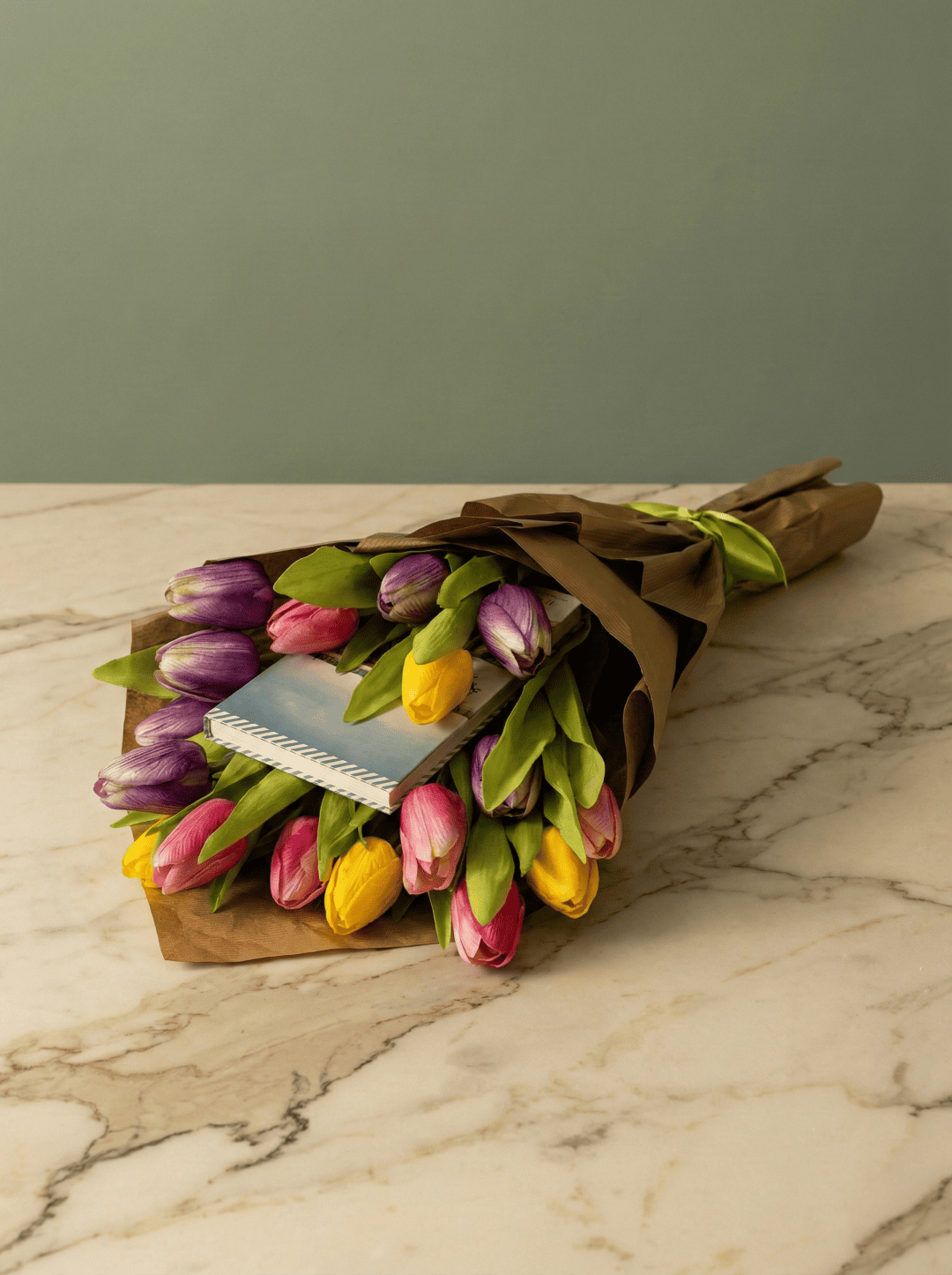 bouquet letterario Composizione floreale creativa con libro per regalo di laurea o compleanno su sfondo verde salvia.